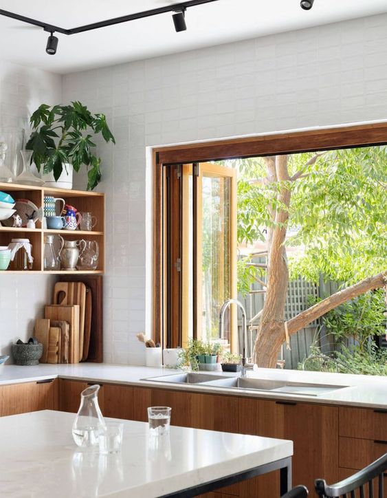 a chic modern kitchen with stained cabinets, an open shelf, a pass through window thay is folding and that allows opening it to outdoors