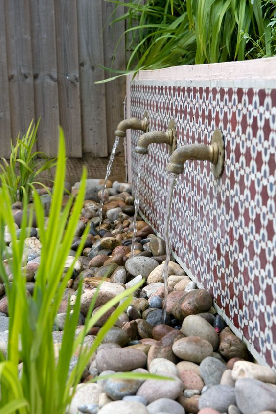 a classy East inspired fountain with bold Moroccan tiles and vintage faucets plus a tray with pebbles where the water goes