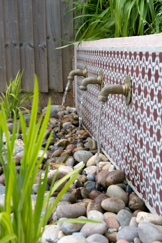 une fontaine élégante d'inspiration orientale avec des carreaux marocains audacieux et des robinets vintage ainsi qu'un plateau avec des galets où va l'eau une fontaine élégante d'inspiration orientale avec des carreaux marocains audacieux et des robinets vintage ainsi qu'un plateau avec des galets où va l'eau