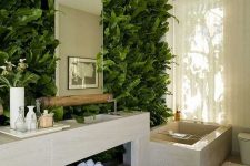 a contemporary bathroom with a living greenery wall, a tiled vanity, a tiled tub and candle lanterns and towels is a chic space