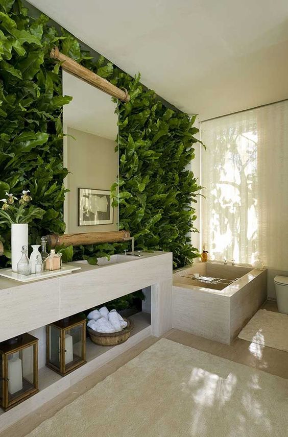 a contemporary bathroom with a living greenery wall, a tiled vanity, a tiled tub and candle lanterns and towels is a chic space