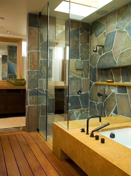 a contemporary bathroom with a touch of rustic chic   a stone wall and stained wooden floors