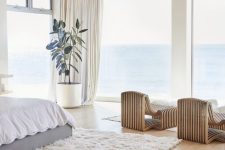 a cozy and stylish contemporary bedroom with catchy bent wooden loungers, a bed, a white fur rug and a statement plant plus sea views