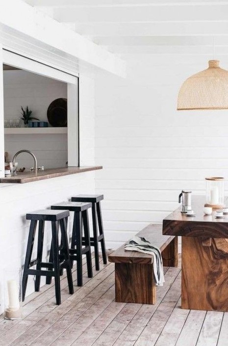 a cozy white pass through space with a narrow windowsill and black stools plus a real dining zone