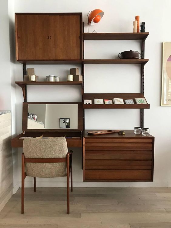 a dark stained storage wall unit with open shelves and cabinets plus a desk with a mirror under it is a cool option for a mid-century modern space