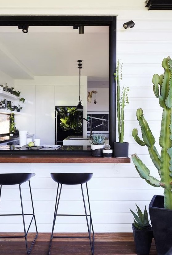 a desert-inspired boho chic space with a dark-stained windowsill and black modern stools