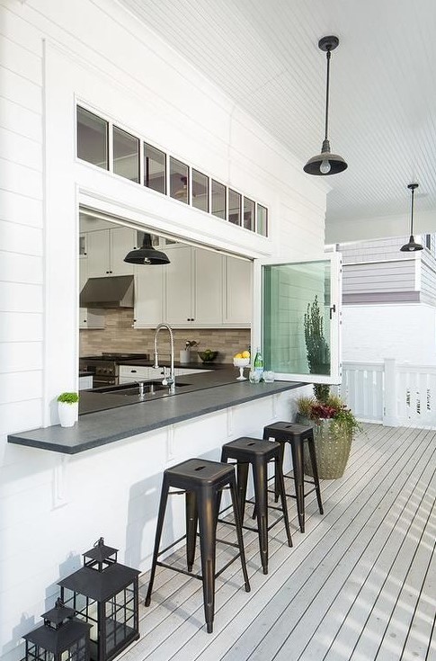 a foldable window with a windowsill and black stools plus black lanterns to compose a nice outdoor eating space
