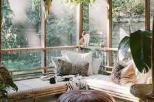 a gorgeous boho screened patio with a corner rattan bench with boho pillows, leather poufs, potted greenery is super welcoming