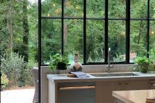 a grey gallery kitchen with neutral stone countertops, a glazed wall with forest views that become part of decor
