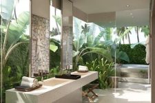 a jaw-dropping tropical spa bathroom with glass walls and surrounded with greenery and tropical plants, a tub, wooden stools, a stone vanity and some neutral towels