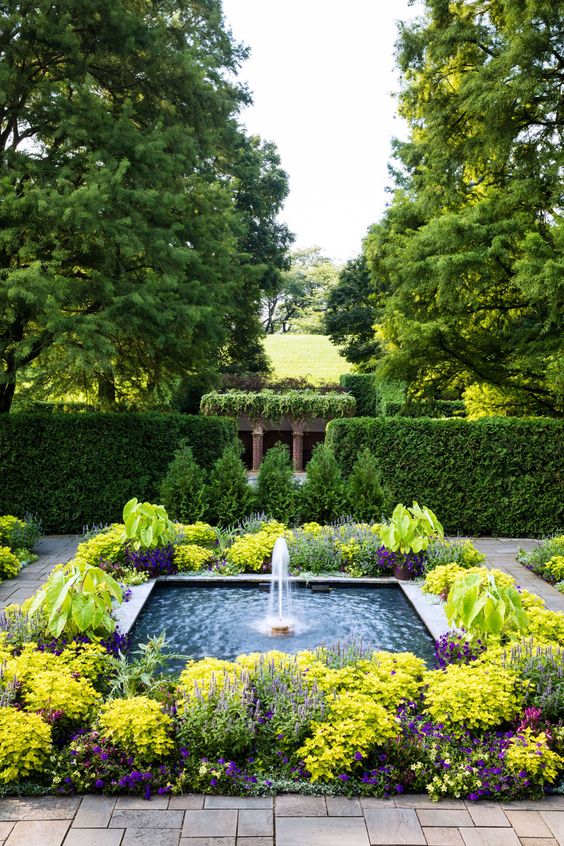une grande fontaine moderne et fraîche entourée de fleurs et de verdure audacieuses est une idée fantastique pour un espace extérieur moderne une grande fontaine moderne et fraîche entourée de fleurs et de verdure audacieuses est une idée fantastique pour un espace extérieur moderne
