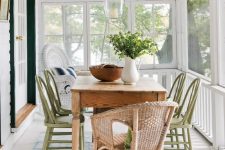 a lovely neutral screened porch with a stained table, green and neutral wicker chairs, some greenery – a cool dining space