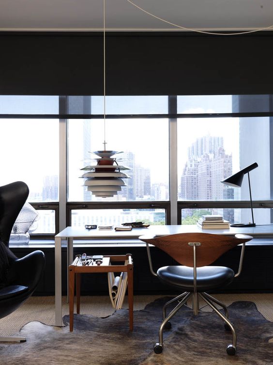 a mid-century modern home office with a glazed wlal, big city views, a sleek desk, a couple of chairs, a magazine stand and a pendant lamp
