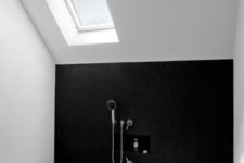 a minimal monochromatic bathroom in black and white, with skylights and a sunken bathtub is a very simple and stylish space