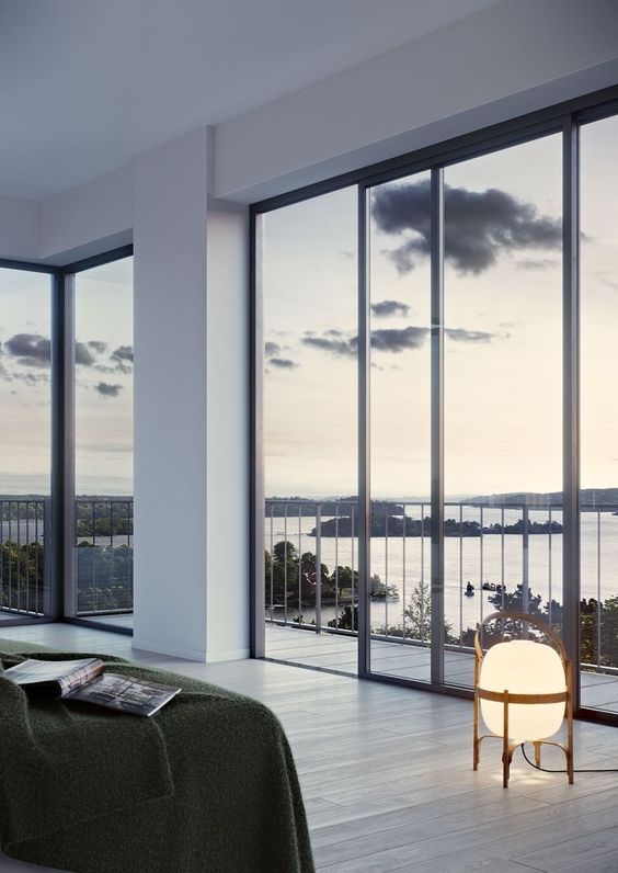 a minimalist bedroom with a bed, some lamps and gorgeous sea views through glass walls is a fantastic space to be