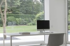 a minimalist white home office with large windows that let you enjoy the garden, a sleek white desk and a chair is a lovely space to work in
