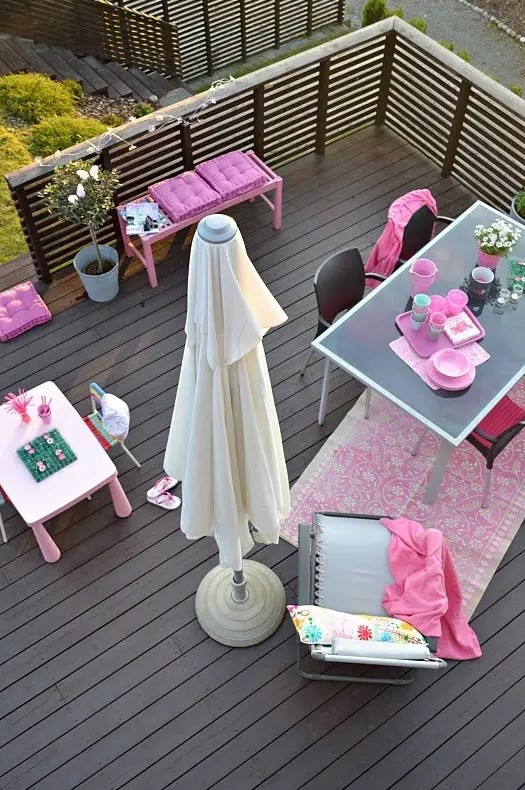 a modern balcony terrace with simple furniture, a kids' drawing nook, bright pink touches and a potted plant for a fresh feel