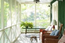 a modern screened porch with wicker chairs with bright pillows and cushions, table lamps, stools and greenery is lovely