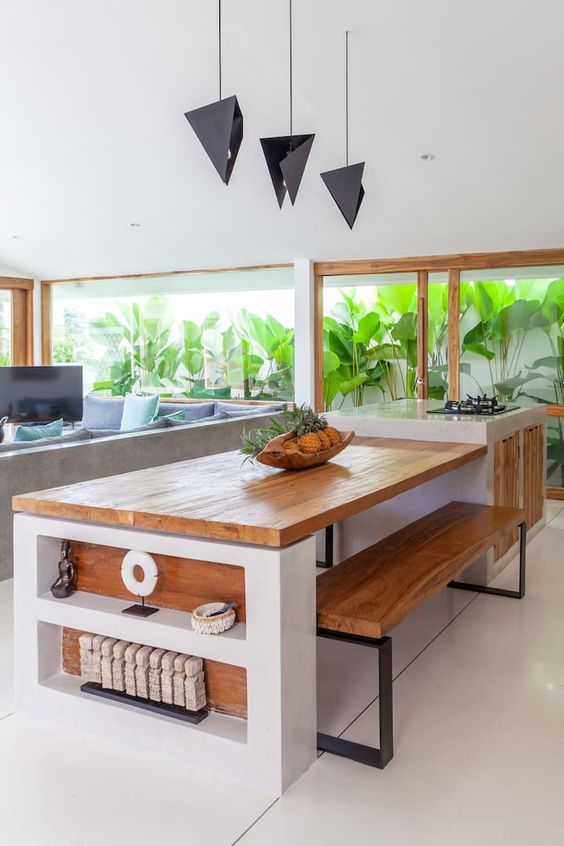 a pretty contemporary kitchen in white, with stained wood and a glazed wall that opens on a tropical garden