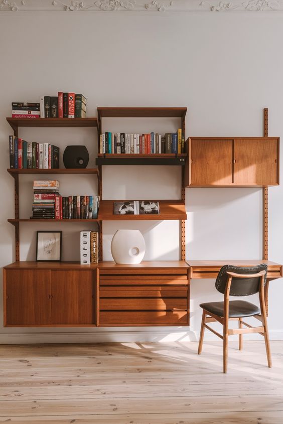 a rich-stained modern wall storage unit with open shelves and drawers and cabinets plus a small desk