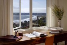 a romantic and dreamy home office with a window and coastal and sea views, a vintage stained desk, an orange chair and some books