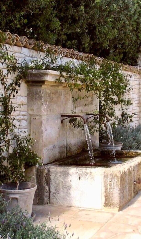 une fontaine simple et élégante composée de deux robinets et d'une baignoire en pierre, entourée de verdure, est incroyable une fontaine simple et élégante composée de deux robinets et d'une baignoire en pierre, entourée de verdure, est incroyable