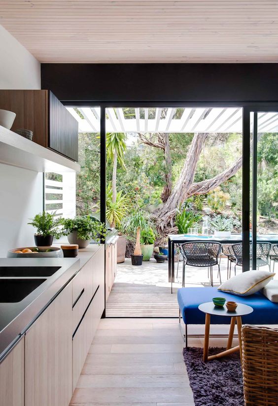 a sleek contemporary kitchen with a glazed wall that can be removed with sliding doors to connect the garden to the kitchen