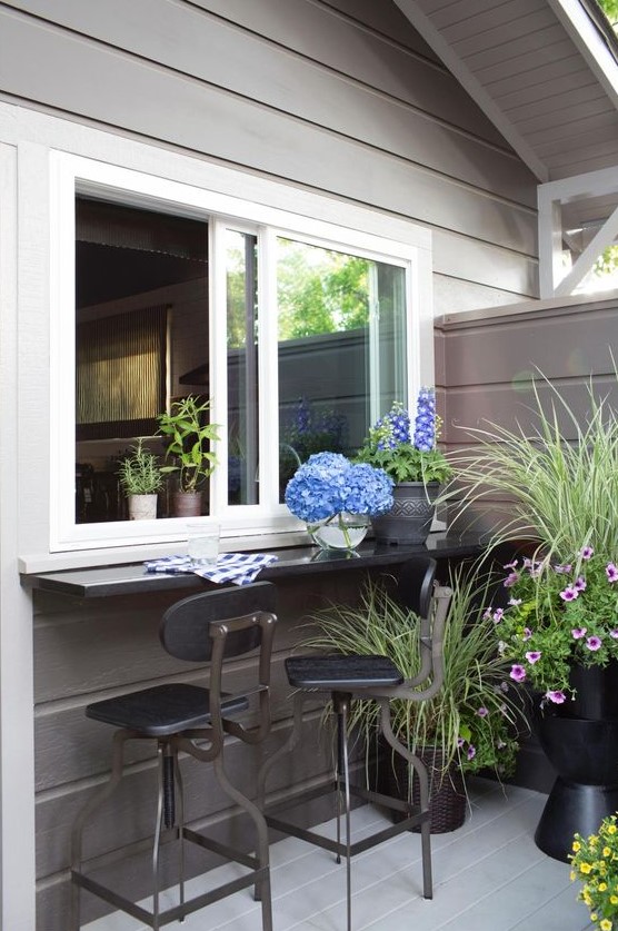 a sliding window with a black windowsill and some stools to have drinks here, potted blooms for creating an ambience