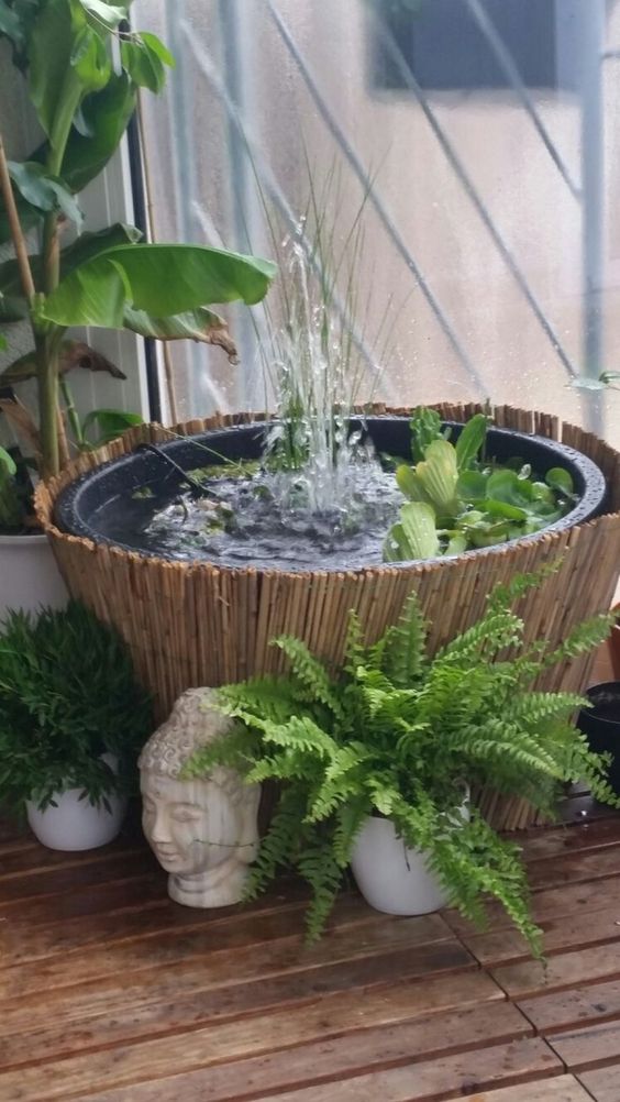 a small and pretty fountain in a bowl with greenery surrounded with a potted plants and with a bamboo cover is a lovely idea for an Asian garden