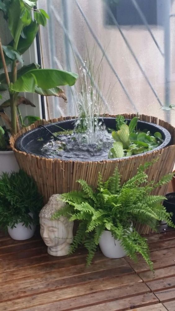 une petite et jolie fontaine dans un bol avec de la verdure entourée de plantes en pot et avec une couverture en bambou est une belle idée pour un jardin asiatique une petite et jolie fontaine dans un bol avec de la verdure entourée de plantes en pot et avec une couverture en bambou est une belle idée pour un jardin asiatique
