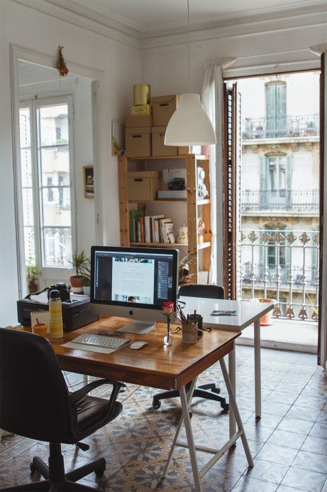 a small yet cozy home office with wooden storage units, a tiled floor, a couple of small desks, black chairs and a view of Paris