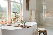 a sophisticated spa-inspired bathroom with a large shower space, a modenr oval tub, a stool and a wooden shelf, tall and thin candles