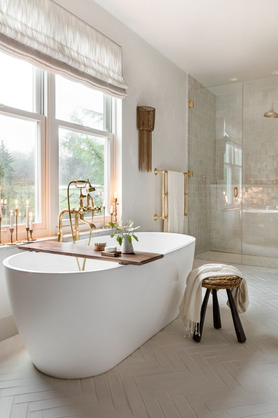 a sophisticated spa-inspired bathroom with a large shower space, a modenr oval tub, a stool and a wooden shelf, tall and thin candles