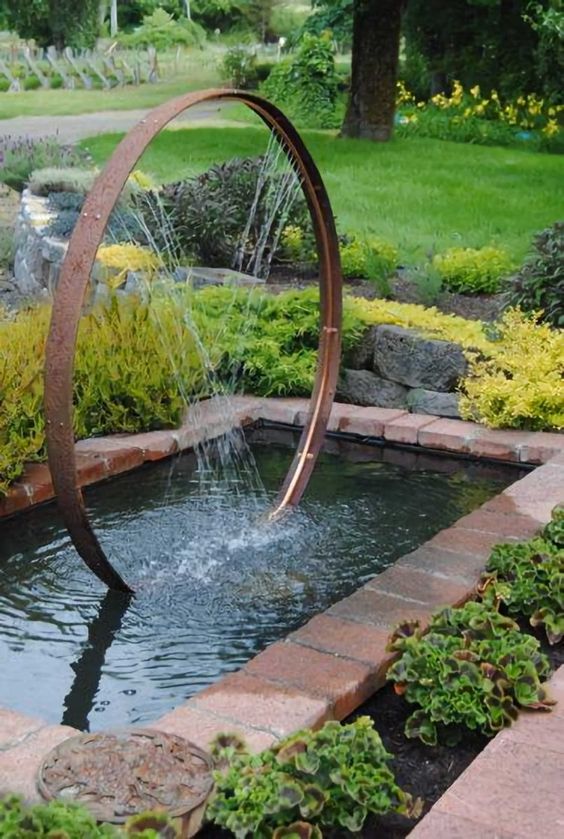 un étang de jardin frais avec une fontaine une fontaine moderne super créative composée d'une roue en métal et placée dans un étang attirera l'attention dans votre jardin