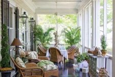 a vintage-inspired screened porch with wicker furniture and printed upholstery, potted plants and decor and lanterns