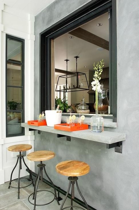 an industrial space with a concrete windowsill, a roll up window, metal and wood stools looks bold and catchy