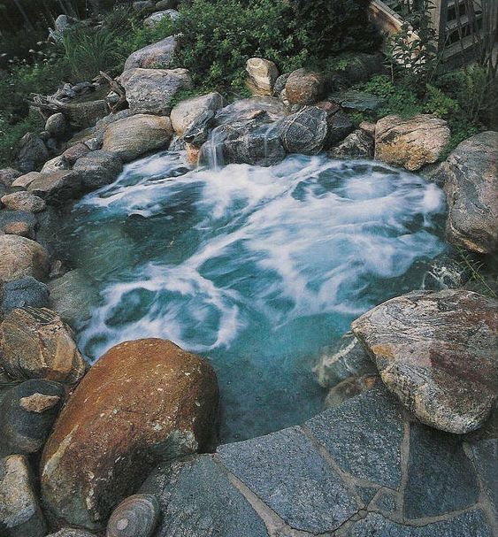 an outdoor hot tub fully clad with rocks and stones looks all natural and relaxes you even more thanks to that