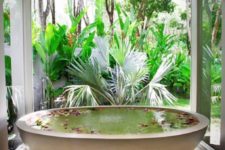 an oval bathtub placed on pebbles feels like a real spa and can be opened up to outdoors any time