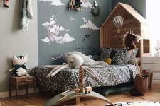 a Nordic kid’s bedroom with an accent corner, a wooden house-shaped bed with printed bedding, layered rugs, buntings and racks