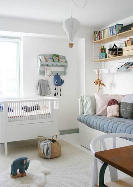 a Nordic kid's room with a daybed, a crib, a shelving unit and a rack, some pastel decor and bedding