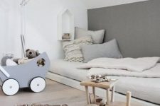 a Nordic kids’ room with a low bed, a floor lamp, some simple and wooden toys looks airy and very serene