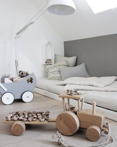 a Nordic kids' room with a low bed, a floor lamp, some simple and wooden toys looks airy and very serene