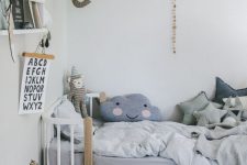 a Nordic kid’s room with a white bed and a nightstand, ledges with books, pastel bedding and a gallery wall