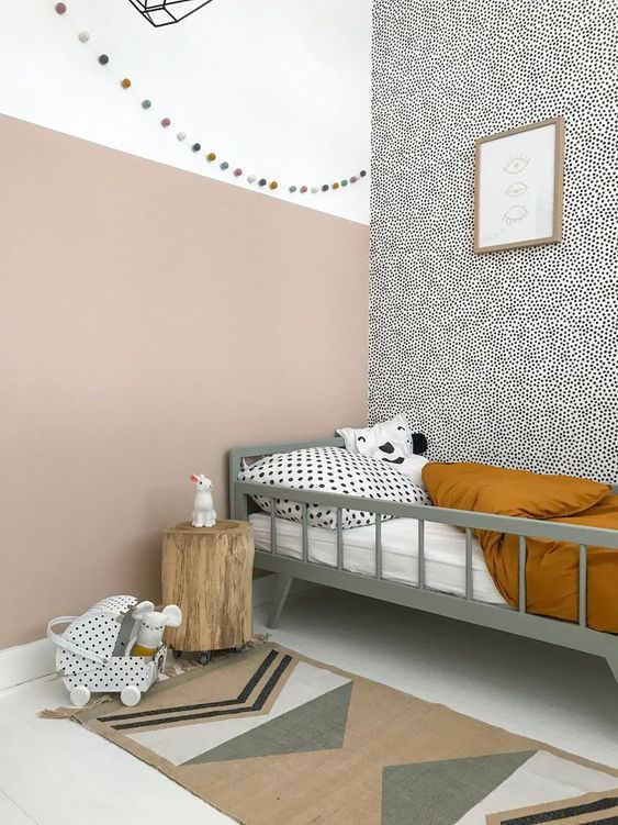a Nordic kid's space done with plenty of color and print, with a grey bed and printed bedding, a printed wall, a tree stump and a printed rug