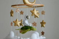a beautiful and inspiring mobile with gold stars and a moon, an astronaut flying on a turtle and clouds is a super cool idea