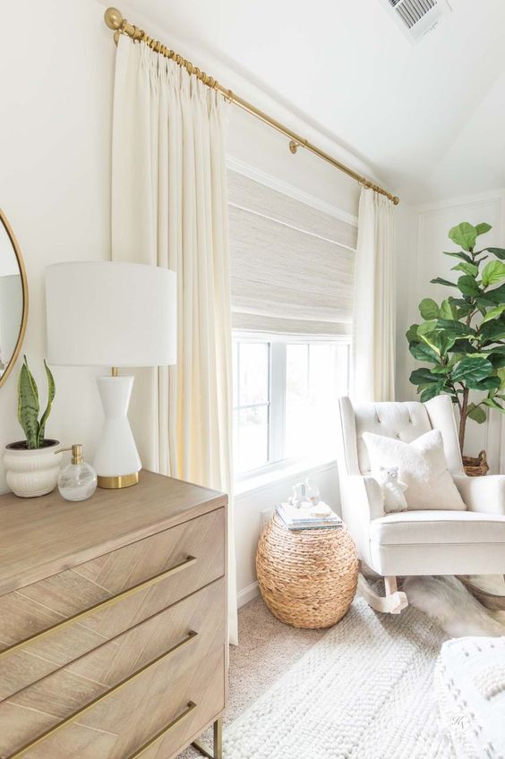 a beautiful creamy space with a neutral Roman shade and creamy curtains to block out the sun when the baby's sleeping