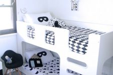 a black and white Nordic kids’ room with accent walls, a white bunk bed with black and white bedding and a black chair