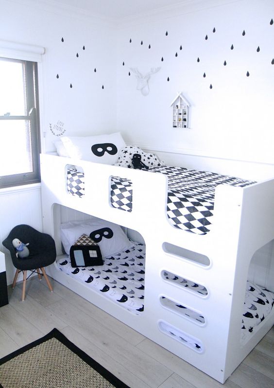 a black and white Nordic kids' room with accent walls, a white bunk bed with black and white bedding and a black chair