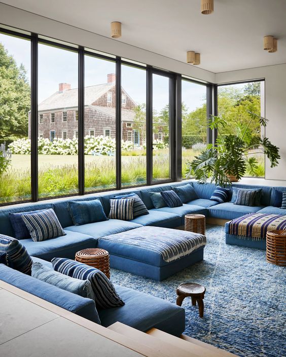 a blue conversation pit with a large sofa that takes three sides, lots of pillows, some woven coffee tables is wow