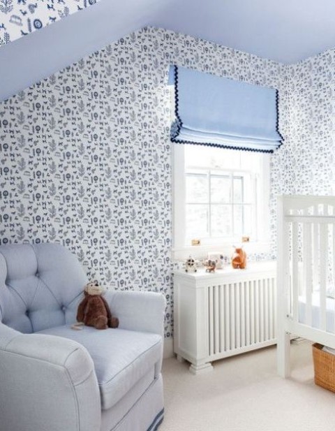 a blue cottage nursery with wallpaper walls, blue textiles and upholstery plus white furniture